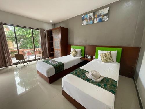 a hotel room with two beds and a table at Melati Kuta Lombok in Kuta Lombok
