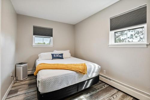 a small bedroom with a bed and two windows at Spacious Colonial Large Groups Fire Pit in Brewer