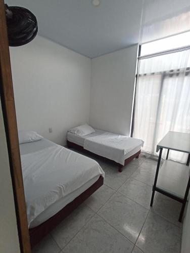a bedroom with two beds and a table and a window at Maná Quinta Campestre in Carmen de Apicalá