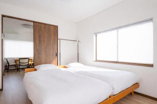 two beds in a room with two large windows at 狐狐 Coco in Kyōto