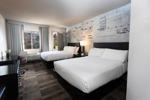 a hotel room with two beds and a desk at Silver Sevens Hotel and Casino, a Wyndham Garden in Las Vegas