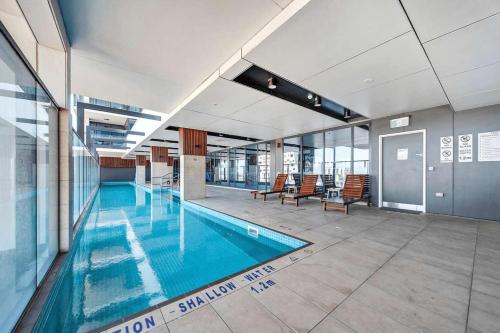 a large swimming pool in a building with chairs at The elegant 1BR CBD Apt - City view - Parking in Adelaide