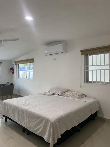 a bedroom with a large bed in a white room at Minimalist house with pool and patio in Chicxulub
