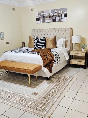 a bedroom with a bed with a bench and a table at Cozy Corner Monavale in Harare