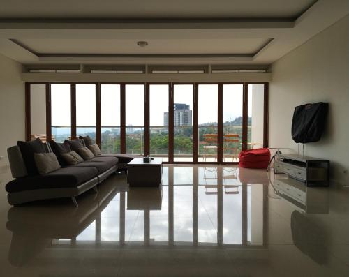 a living room with a couch and large windows at Roemah Asri Villa - Resor Dago Pakar in Bandung