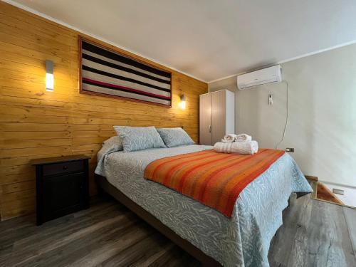 a bedroom with a bed and a wooden wall at Vicuña Lodge in San Pedro de Atacama