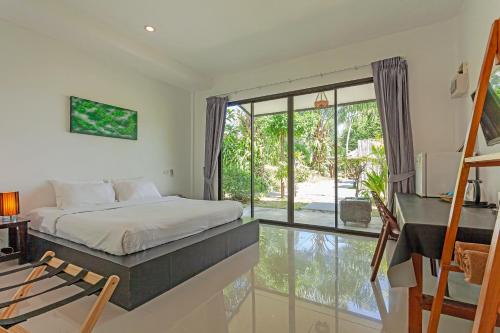 a bedroom with a bed and a large window at Natai House Resort นาใต้เฮ้าส์ รีสอร์ท in Natai Beach