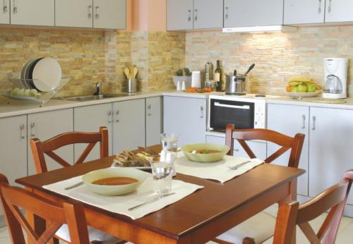 een keuken met een houten tafel met twee kommen erop bij Over Sea Rooms & Villas in Loutra Edipsou