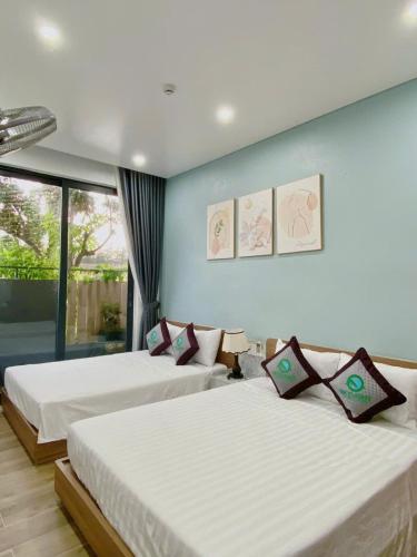 a bedroom with two beds and a large window at Homestay SkyLight in Dong Hoi