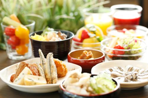 a table with plates of food and bowls of food at Dormy Inn Kagoshima in Kagoshima