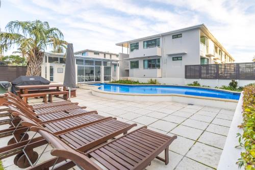 a patio with chairs and a swimming pool at Capri on Pilot Bay in Mount Maunganui