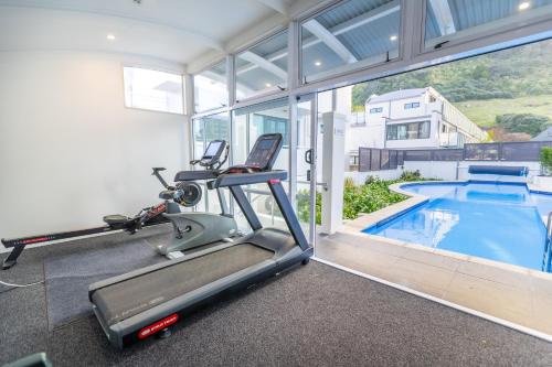 a gym with a treadmill and a swimming pool at Capri on Pilot Bay in Mount Maunganui