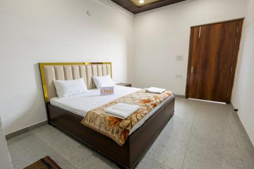 a bedroom with a bed with white sheets and a wooden door at Omji Ashram - Ramnagar 10 min from Shri Banke Bihari Temple in Vrindāvan