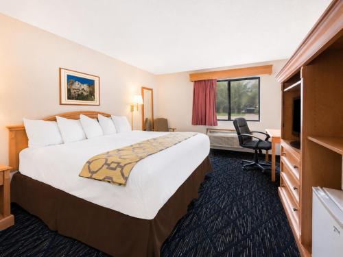 a hotel room with a large bed and a television at Baymont by Wyndham Hot Springs in Hot Springs