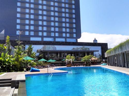 a large swimming pool in front of a tall building at Gammara Hotel Makassar in Makassar