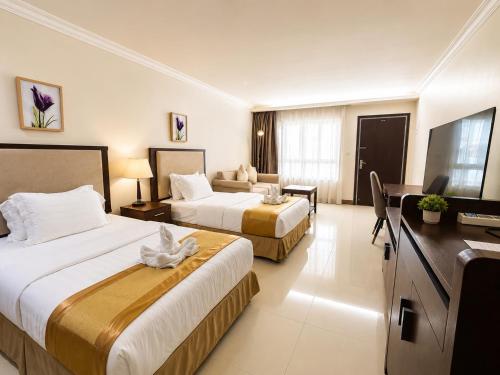 a hotel room with two beds and a couch at Plaza Hotel in Dili