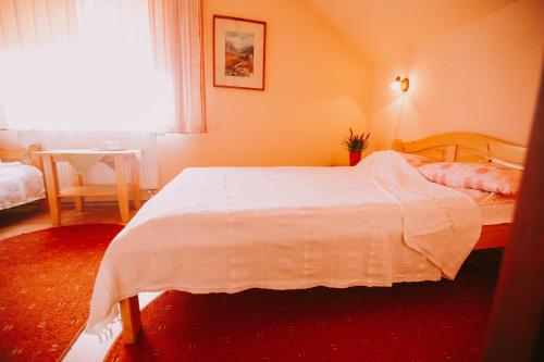 a bedroom with a white bed and a window at Bosnyák Panzió in Odorheiu Secuiesc