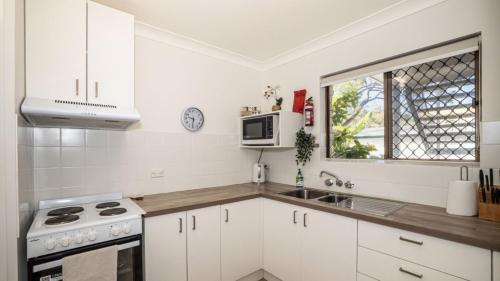a white kitchen with a stove and a microwave at Great Views, Ground Floor Unit in Bongaree