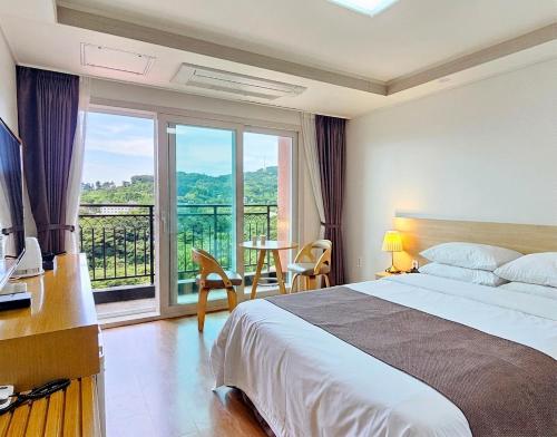 a hotel room with a bed and a large window at Jeju Lavender Hotel in Seogwipo