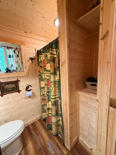 a bathroom with a toilet in a wooden cabin at The Dapper Duck Log Cabin in Cosby