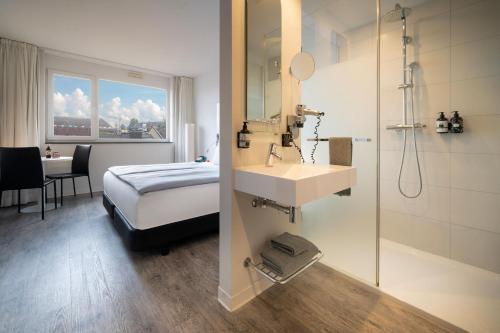 a bathroom with a bed and a sink and a shower at INNSiDE by Meliá Aachen in Aachen