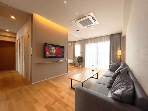 a living room with a couch and a tv on a wall at CONTEL BASE Tokyo in Tokyo