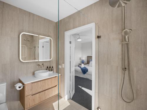a bathroom with a shower and a sink and a mirror at The Point Coolum in Coolum Beach