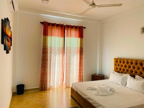 a bedroom with a bed and a colorful curtain at willow Blossoms in Pannipitiya