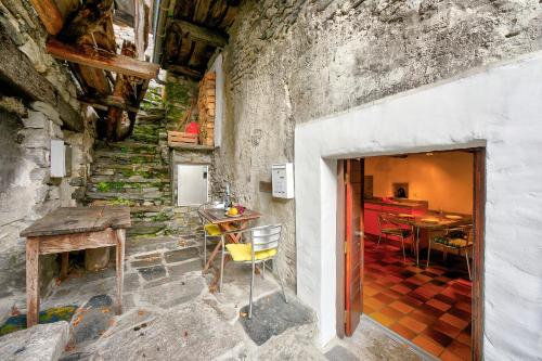 a stone walled room with a table and chairs at Rustico Caterina - Corippo- Happy Rentals in Corippo