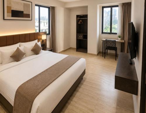 a bedroom with a bed and a desk with a television at Hotel Pune Grand in Pune