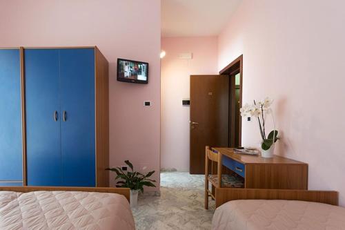 a bedroom with a bed and a desk with a blue cabinet at Hotel Roma in Pineto
