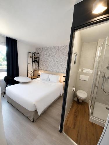 a bedroom with a large white bed and a shower at Kyriad Hôtel La Fleche in La Flèche