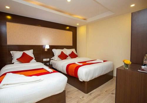 a hotel room with two beds with red pillows at Hotel Plaza in Bāndarban