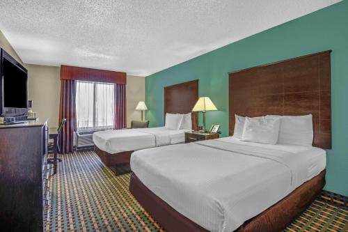 a hotel room with two beds and a television at La Quinta Inn by Wyndham Columbia SE Fort Jackson in Columbia