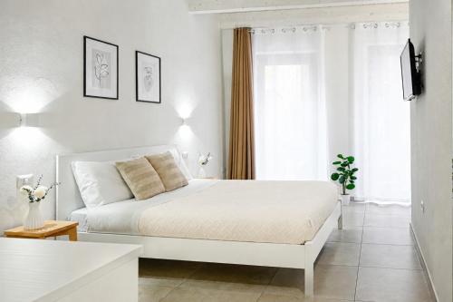 a white bedroom with a white bed and a window at DoMe Affittacamere in Iglesias