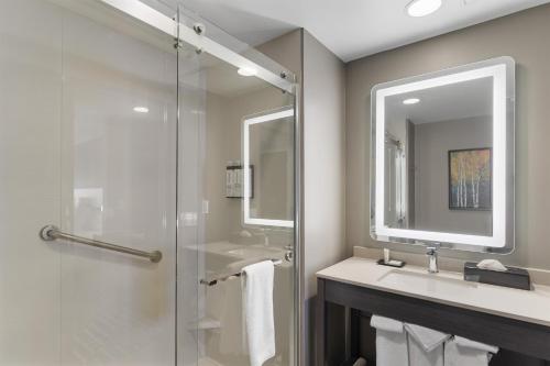a bathroom with a shower and a sink and a mirror at Hyatt House Thunder Bay in Thunder Bay