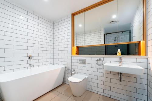 a bathroom with a tub and a toilet and a sink at Rouse Hills TownCentre luxury accommodation in Kellyville