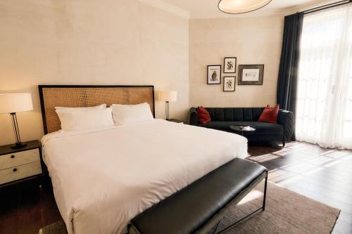 a bedroom with a large white bed and a couch at The Strand Hotel in Sydney