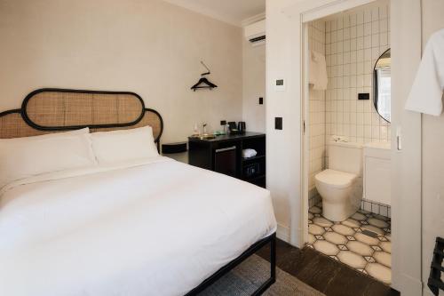 a bedroom with a bed and a bathroom with a toilet at The Strand Hotel in Sydney