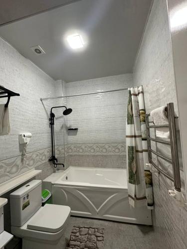 a bathroom with a white tub and a toilet at GRAND SARBON HOTEL in Qarshi