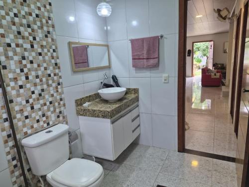 a bathroom with a white toilet and a sink at Quarto privativo em Guriri casa de praia in São Mateus