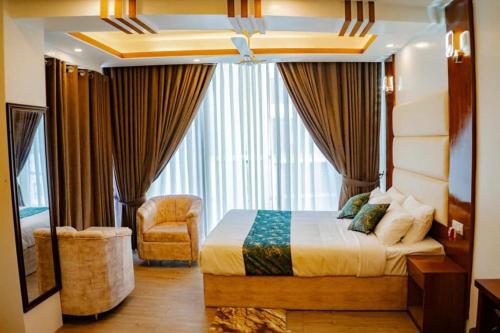 a bedroom with a bed and a chair and a window at The Elegance Hotel & Suites in Chittagong