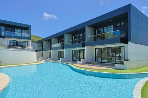 a building with a swimming pool in front of it at Elite Suites Villas Maikhao Phuket in Mai Khao Beach