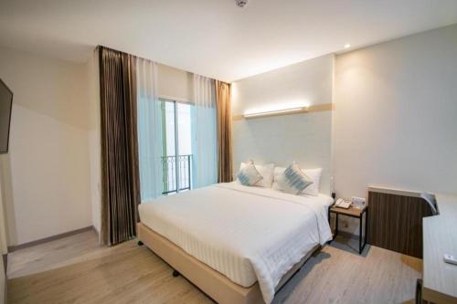 a bedroom with a large white bed and a window at Analynn Hotel in Ban Kohong