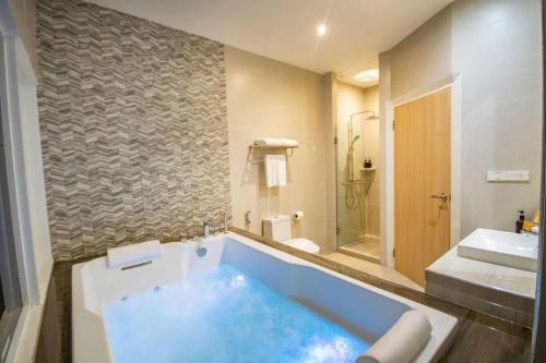 a bathroom with a blue tub and a sink at Analynn Hotel in Ban Kohong