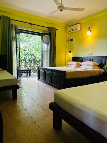 a hotel room with two beds and a balcony at Nature Walk Resort in Kandy