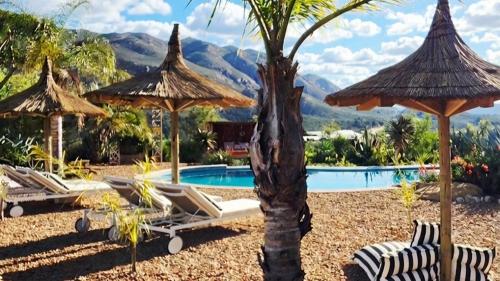 a resort with a swimming pool and umbrellas and chairs at Maison PJURE Boutique Hotel & Spa , Adults Only in Montagu
