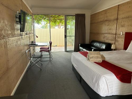 a bedroom with a bed and a desk and a chair at Crossroads Ecomotel in Port Augusta