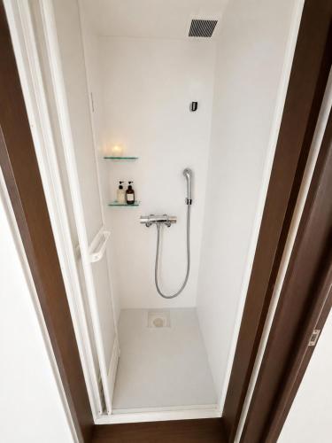 a white bathroom with a shower in a room at ペンションハートウォーマー in Myoko