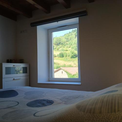 a bedroom with a window with a bed and a dresser at Le Nolan in Cublize